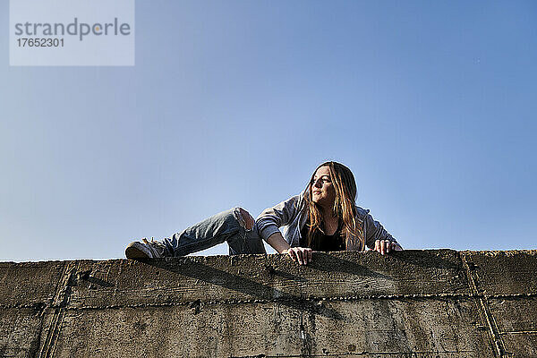 Junge Frau klettert über Betonwand