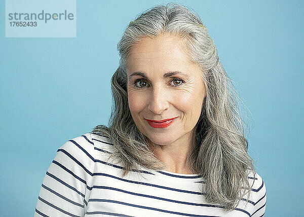 Smiling woman with gray hair against blue background