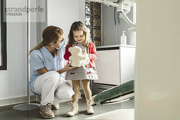 Zahnarzt mit niedlichem kleinen Mädchen  das Stofftier in der Zahnklinik hält