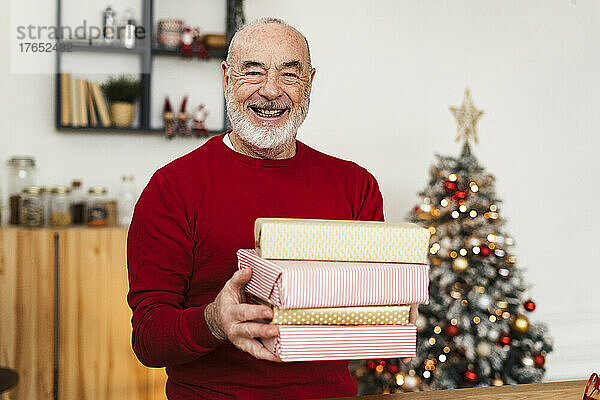Glücklicher älterer Mann hält Geschenkboxen zu Hause