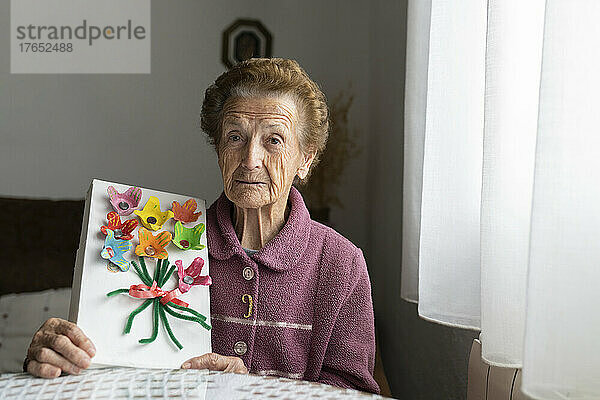 Ältere Frau zeigt Kunsthandwerk am Esstisch