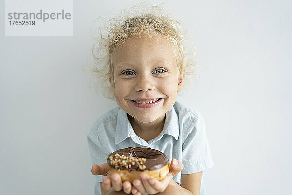 Lächelndes blondes Mädchen  das Donut hält