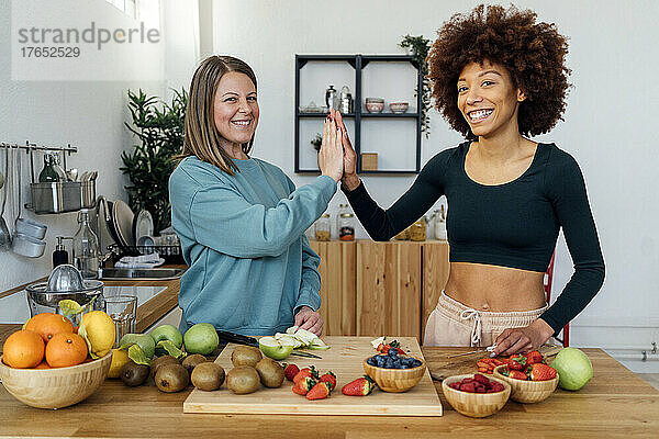 Glückliche Frauen  die sich am Tisch in der Küche gegenseitig High-Five geben