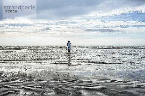 Mädchen steht am Strand im Wasser