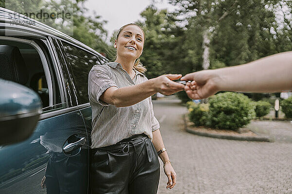 Lächelnde Frau gibt Mann auf Parkplatz Autoschlüssel