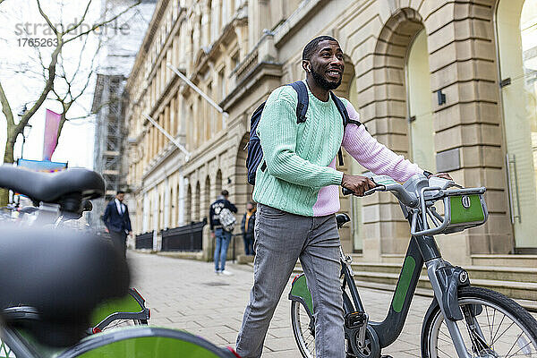 Lächelnder Mann mit Elektrofahrrad geht auf Fußweg