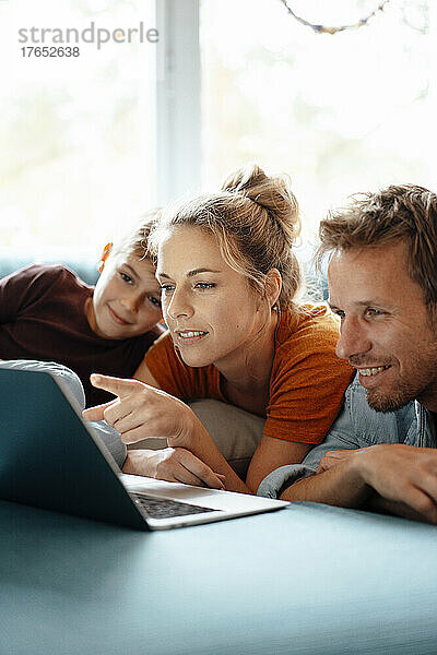 Frau zeigt zu Hause von Mann und Sohn auf Laptop