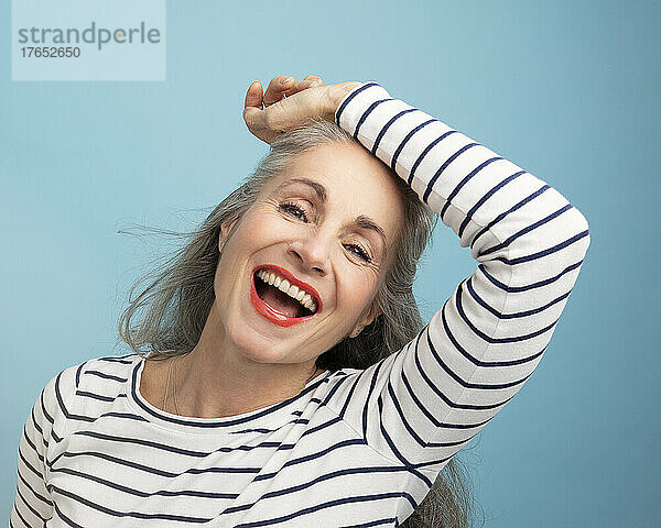 Happy woman with hand on head against blue background