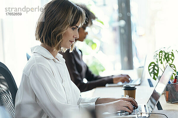Geschäftsfrau und Kollegin nutzen Laptop am Schreibtisch im Büro