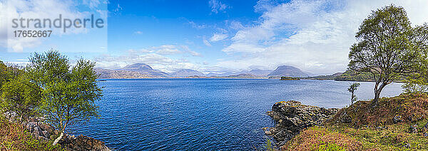 Malerischer Blick auf den blauen See Loch Shieldaig unter bewölktem Himmel