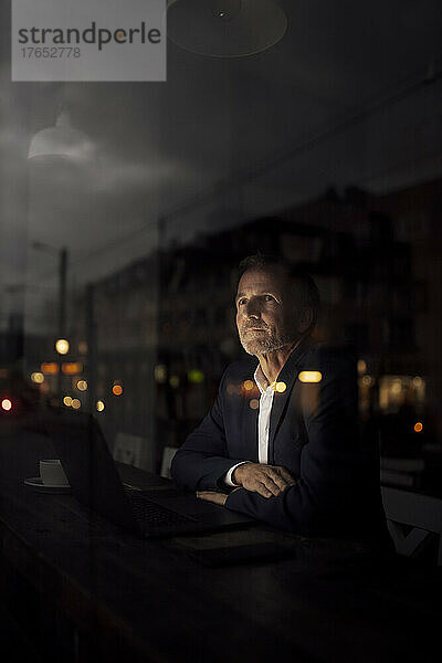 Geschäftsmann sitzt nachts im Dunkeln im Café