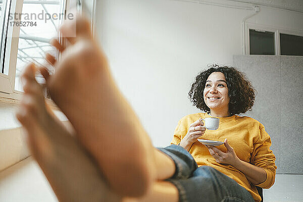 Glückliche schöne Frau  die zu Hause mit einer Kaffeetasse sitzt