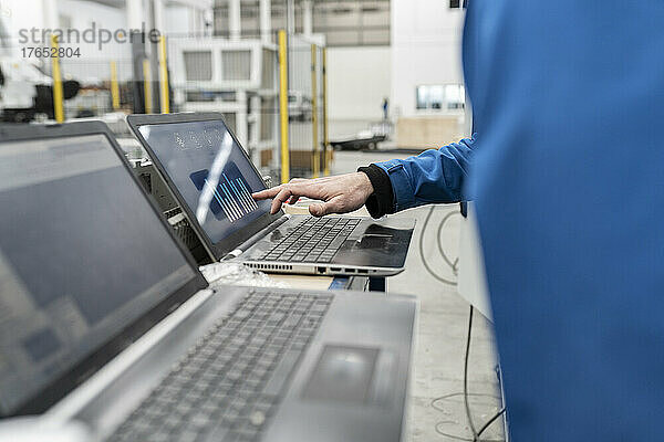 Hand eines Ingenieurs  der in der Fabrik einen Laptop verwendet