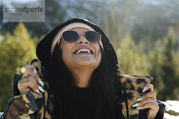 Glückliche Frau mit Sonnenbrille  die an einem sonnigen Tag nach oben schaut