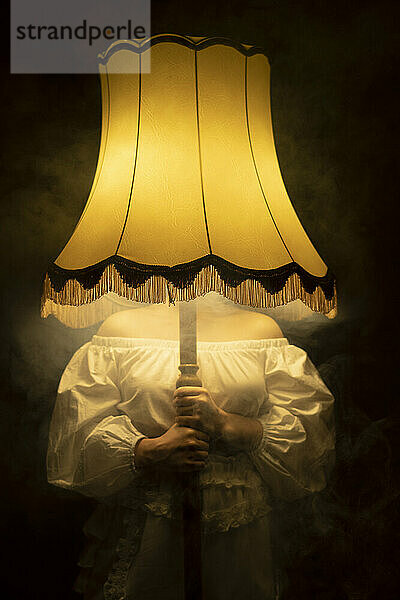 Frau hält beleuchtete rauchige Lampe vor Gesicht
