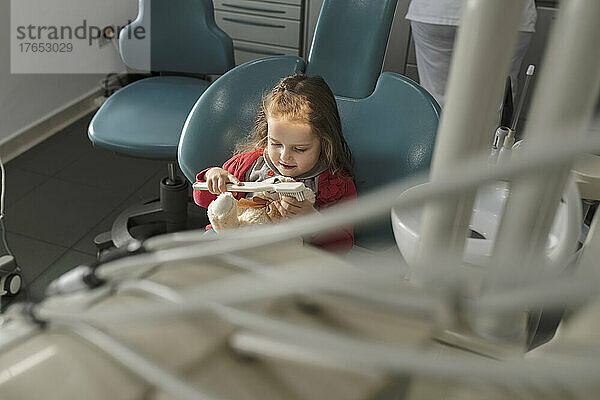 Nettes kleines Mädchen  das in der Zahnklinik mit Zahnbürste spielt