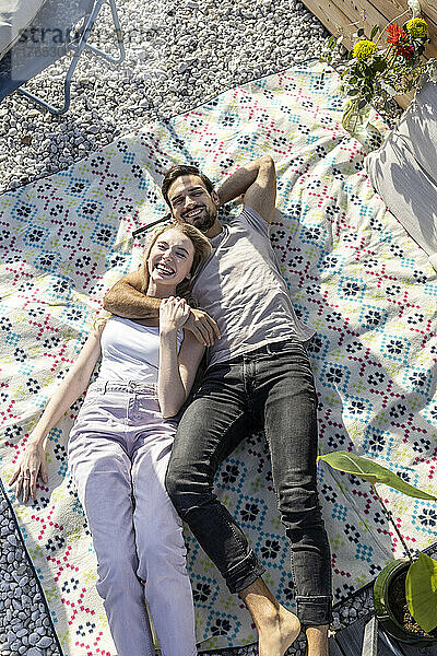 Glückliches Paar liegt auf der Picknickdecke auf der Terrasse