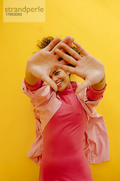 Happy woman gesturing hands lying on yellow background