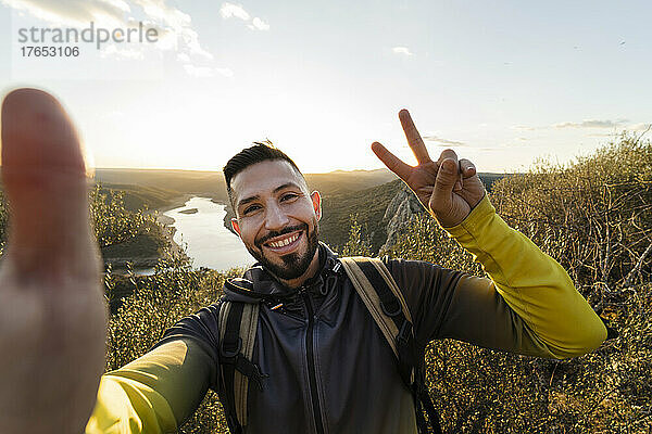 Male hiker making peace gesture while taking selfie in Monfrague National Park