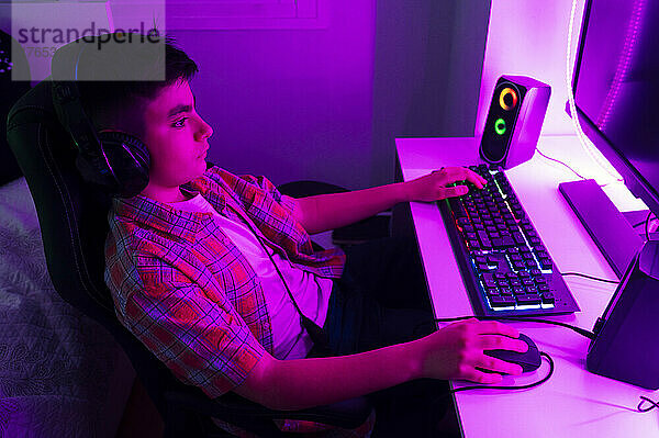 Junge mit Kopfhörern spielt Videospiel am Computer