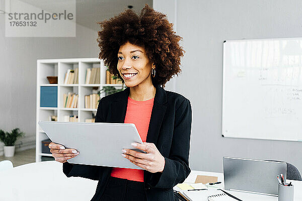 Lächelnde Afro-Geschäftsfrau mit Tablet-PC im Büro