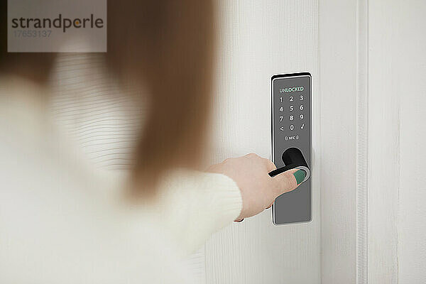Frau öffnet intelligente Haustür mit Zugang per Fingerabdruck