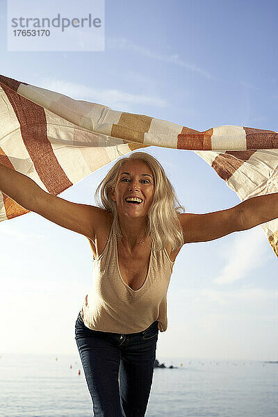 Verspielte Frau mit Schal am Strand