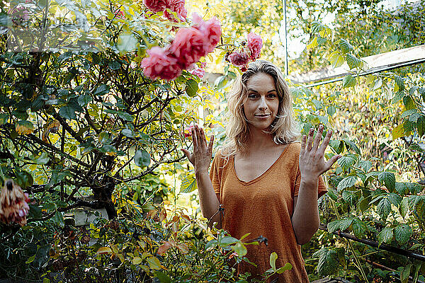 Blonde Frau steht inmitten von Pflanzen im Hinterhof