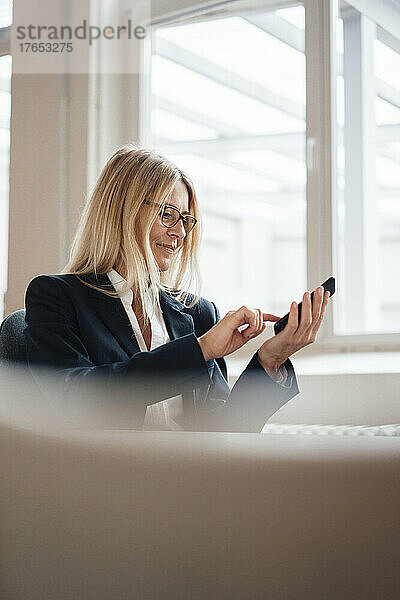 Geschäftsfrau schreibt Textnachrichten auf dem Smartphone im Büro