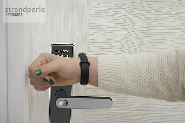Frau scannt Smartwatch  um Haustür zu öffnen