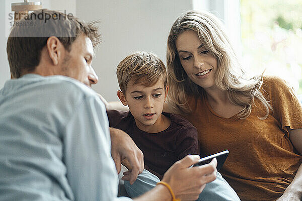 Mann teilt Smartphone mit Frau und Sohn zu Hause