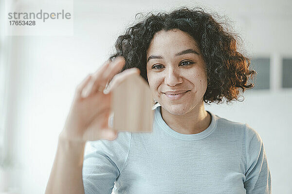 Smiling woman with curly hair holding model house