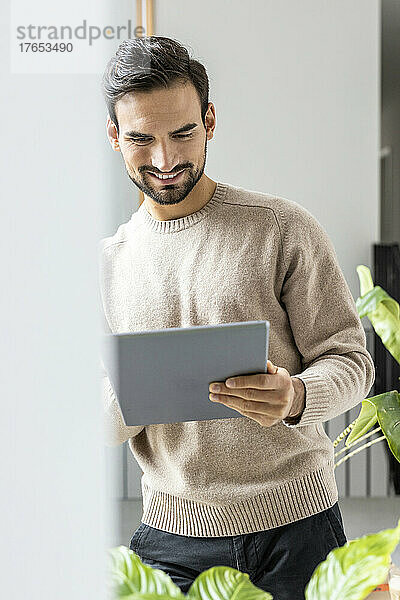 Lächelnder Mann benutzt Tablet-PC zu Hause