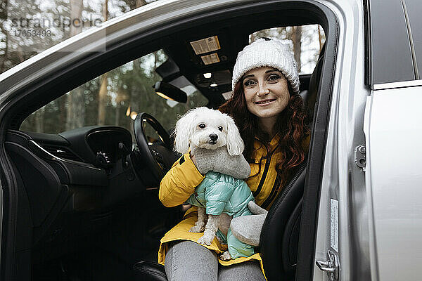 Glückliche Frau mit Hund sitzt im Auto