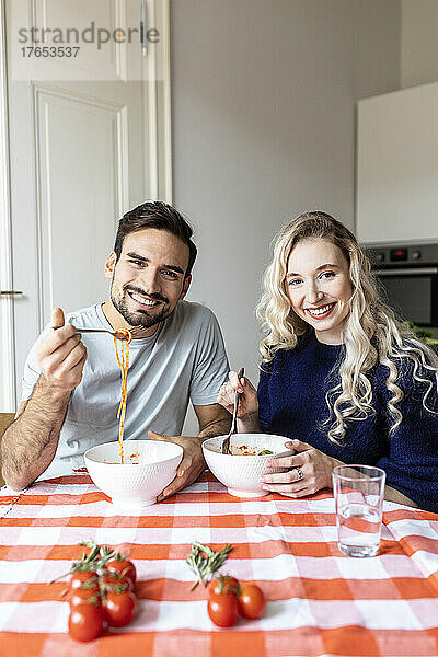 Freund und Freundin essen Nudeln auf dem Esstisch zu Hause