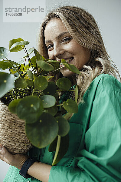Glückliche blonde Frau hält Zimmerpflanze