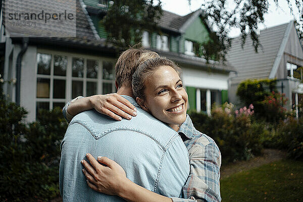 Glückliche Frau umarmt Freund im Hinterhof
