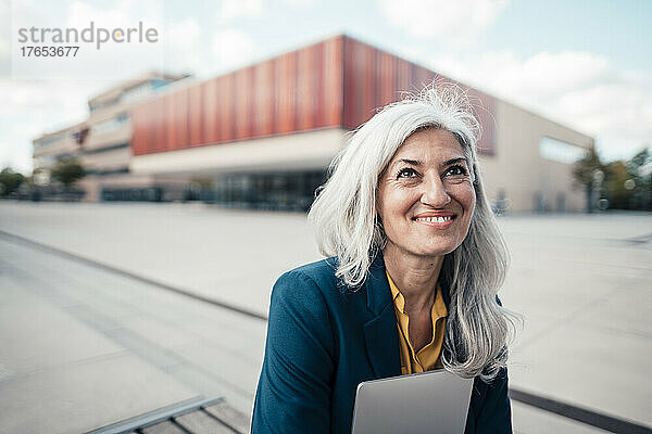 Glückliche Geschäftsfrau mit Laptop im Büropark