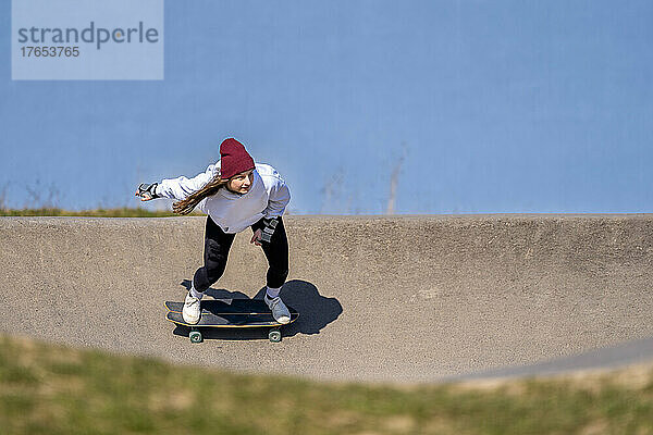 Junge Frau fährt Skateboard auf Pumptrack