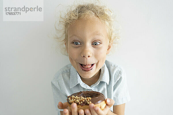 Glückliches blondes Mädchen  das Donut genießt