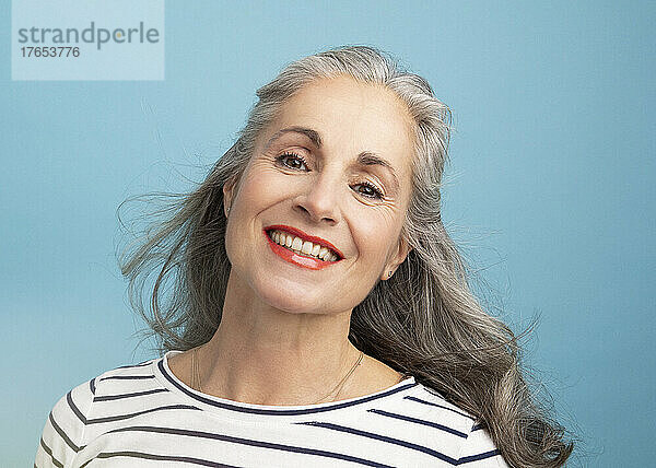 Happy woman with gray hair against blue background