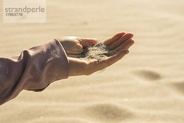 Frau mit Sand in der Hand an einem sonnigen Tag