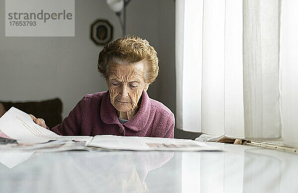 Ältere Frau liest Zeitung am Esstisch
