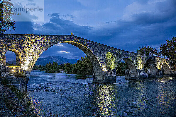 Illuminated Bridge of Arta over Arachthos river at night in Greece