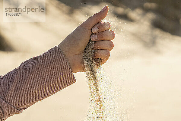 Sand fällt aus der Hand einer Frau