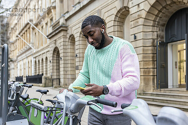 Mann scannt per Smartphone und mietet Fahrrad am Parkplatz