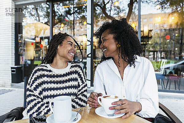Glückliche Kollegen mit Kaffeetassen sitzen im Straßencafé