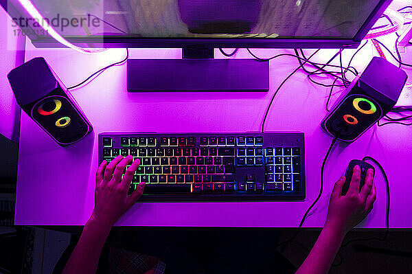 Junge mit Computertastatur und Maus spielt ein Spiel am Computer