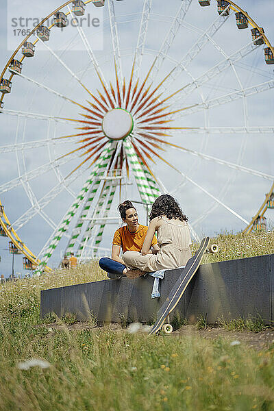 Mutter und Tochter sitzen an einem sonnigen Tag vor dem Riesenrad