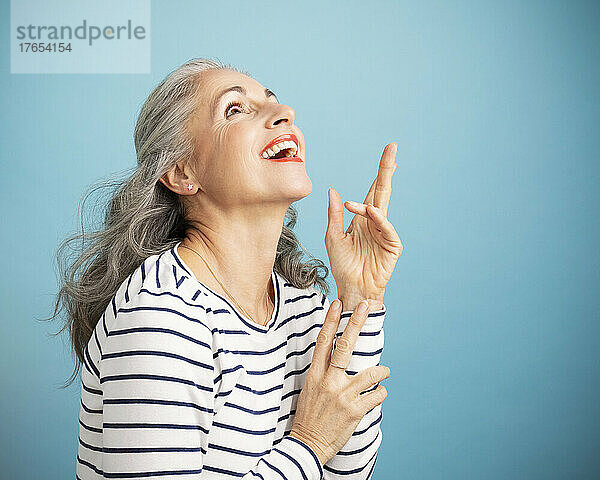 Happy woman gesturing against blue background